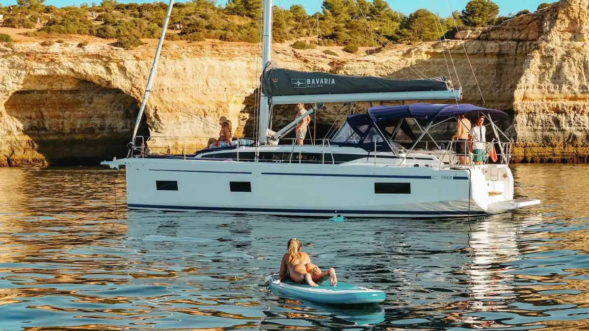 Sailing yacht with white sails off the cliffs near the Benagil sea cave on the Portimão coast, Algarve, Portugal